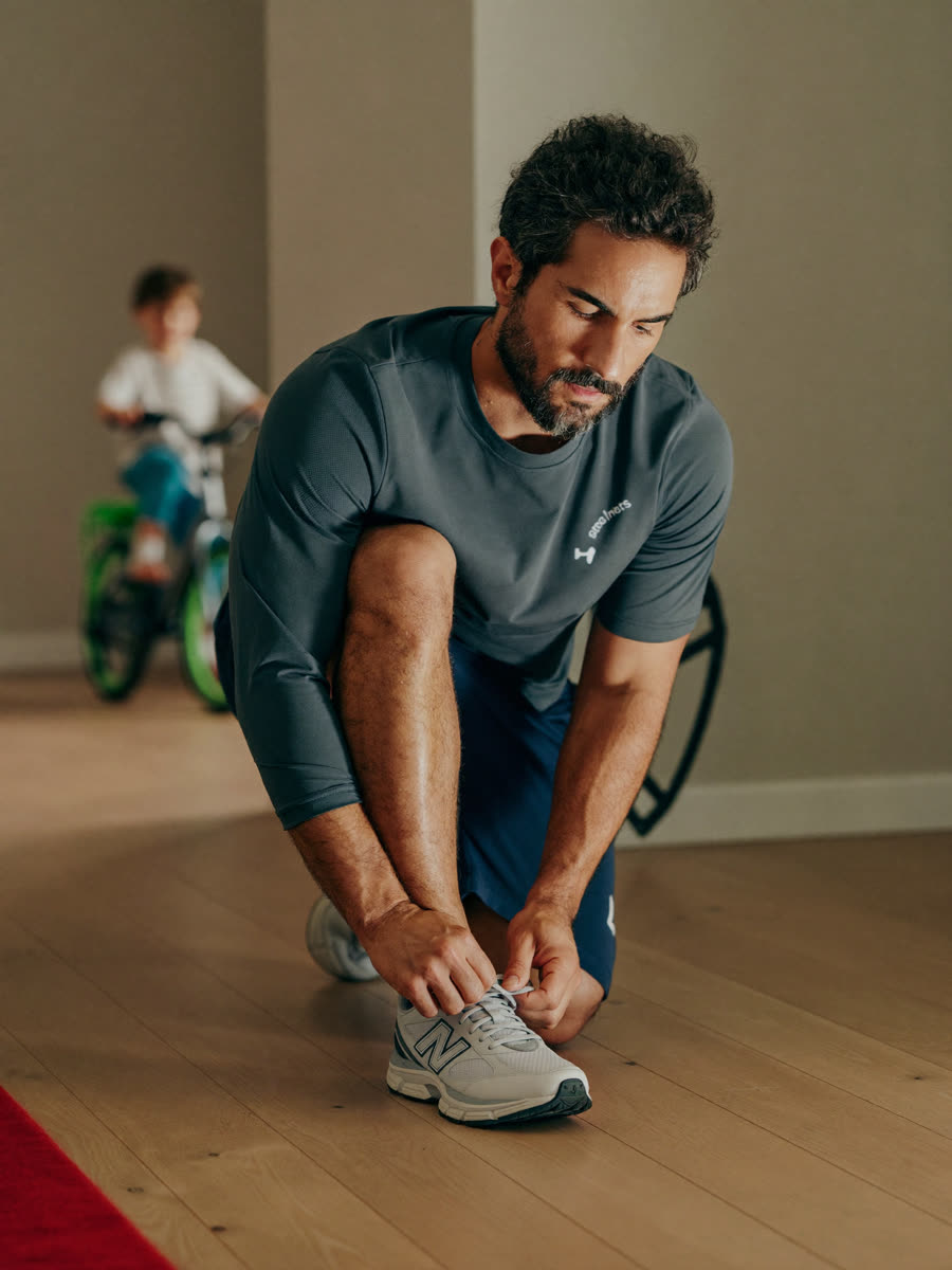 Father tying a running shoe in a hallway in the evening