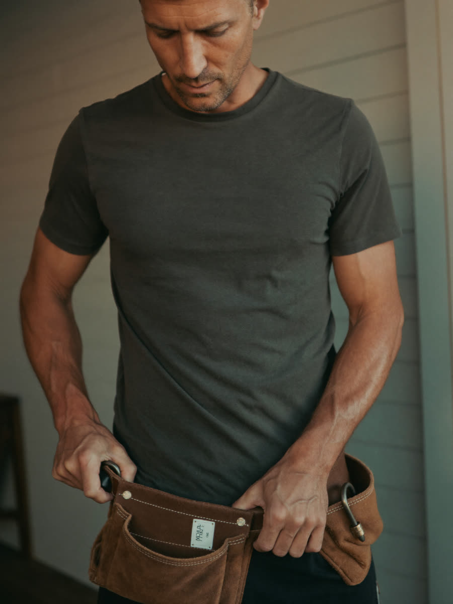 Tradesman taking off his tool belt at the end of a working day